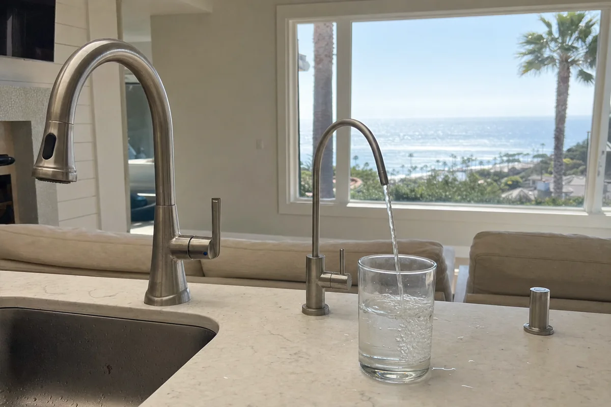 RO drinking water faucet filling a glass beside the main kitchen faucet