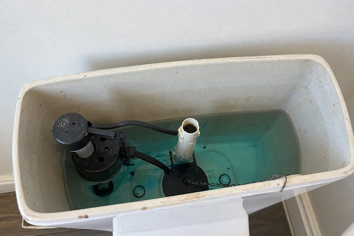 Inside a toilet tank showing the fill valve, flush valve and flapper